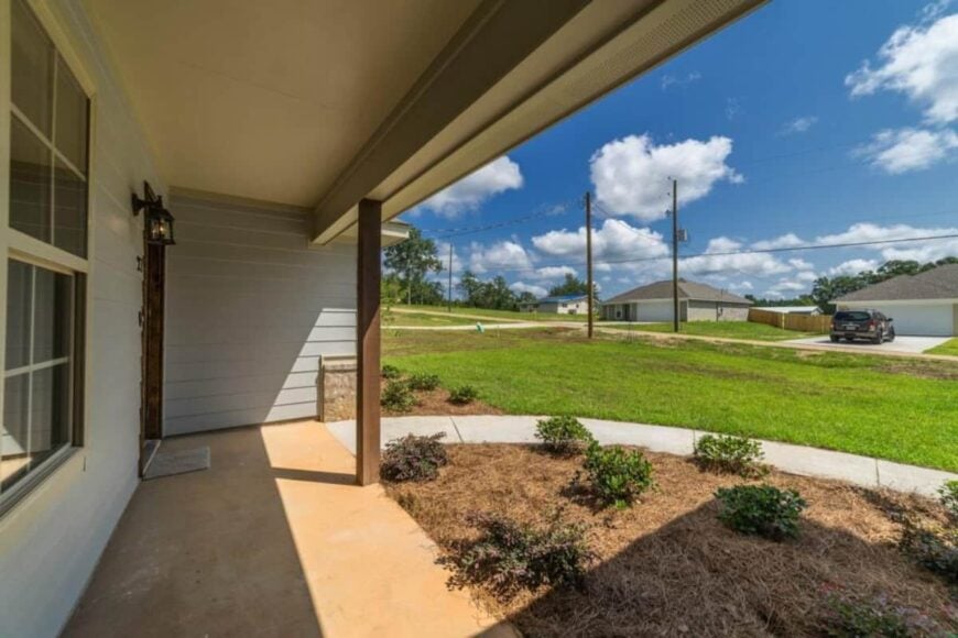 The covered porch has concrete flooring and a sole wooden column.