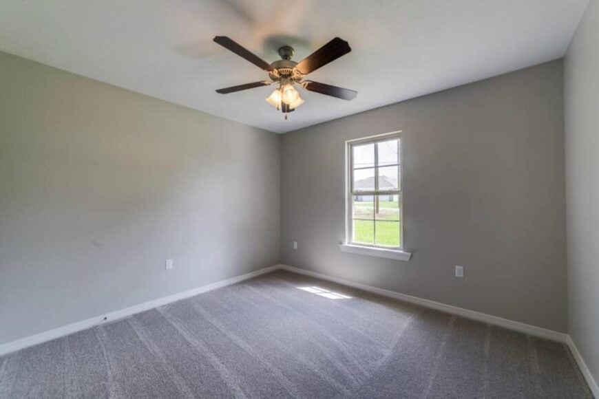 Secondary bedroom with gray walls, carpeted floor, and a ceiling fan.