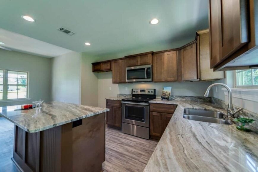 Stainless steel appliances and double sinks under the framed window complete the kitchen.