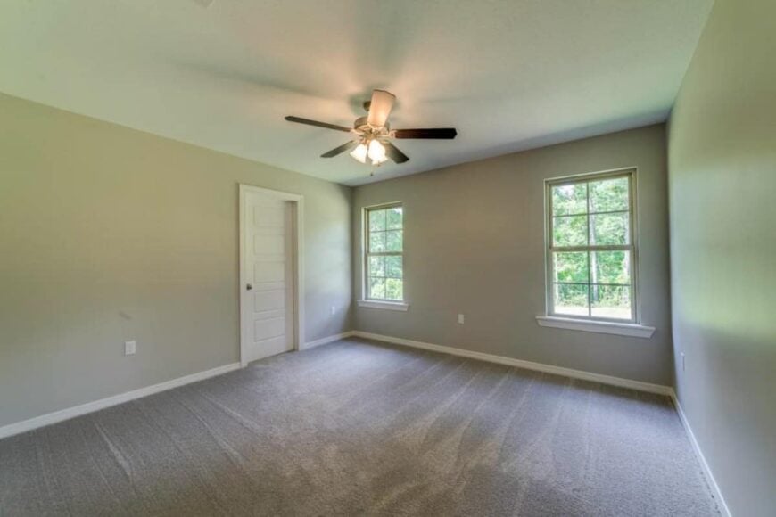 Primary bedroom with carpeted floor, a ceiling fan, and a couple of windows that invite natural light in.