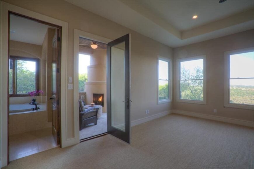 Primary bedroom with a tray ceiling, a spa-like ensuite, and a private porch warmed by a fireplace.