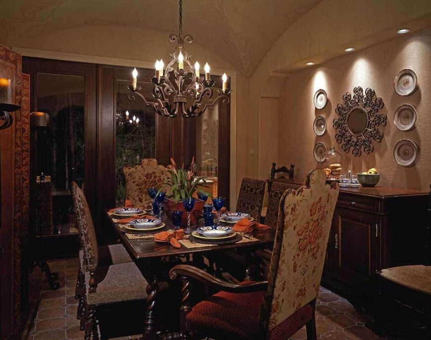 Formal dining room with a rectangular dining set, an ornate chandelier, and a wooden buffet table adorned with a decorative mirror and ceramic plates.