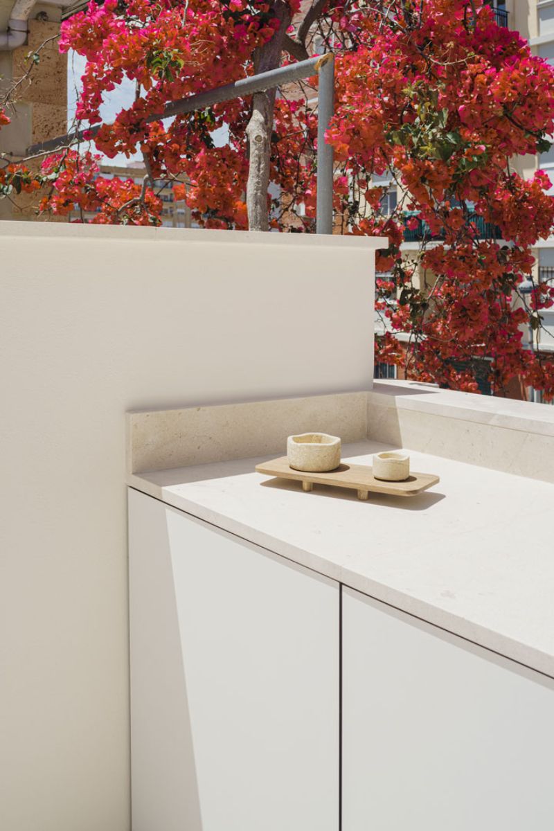 An outdoor kitchen area beside a bougainvillea plant.