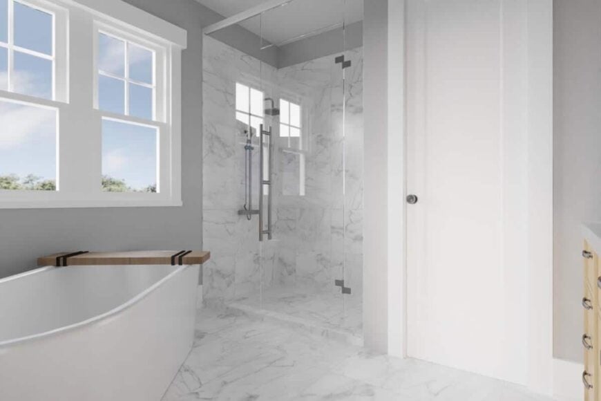 Primary bathroom with a freestanding tub and a walk-in shower clad in white marble tiles.