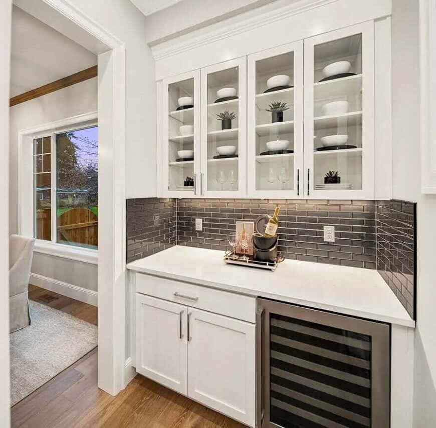 The butler's pantry has glass-front cabinets, a black subway tile backsplash, and a wine fridge.