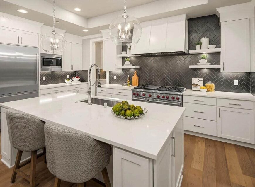 Kitchen with stainless steel appliances, white cabinetry, and a breakfast island fitted with an undermount sink.