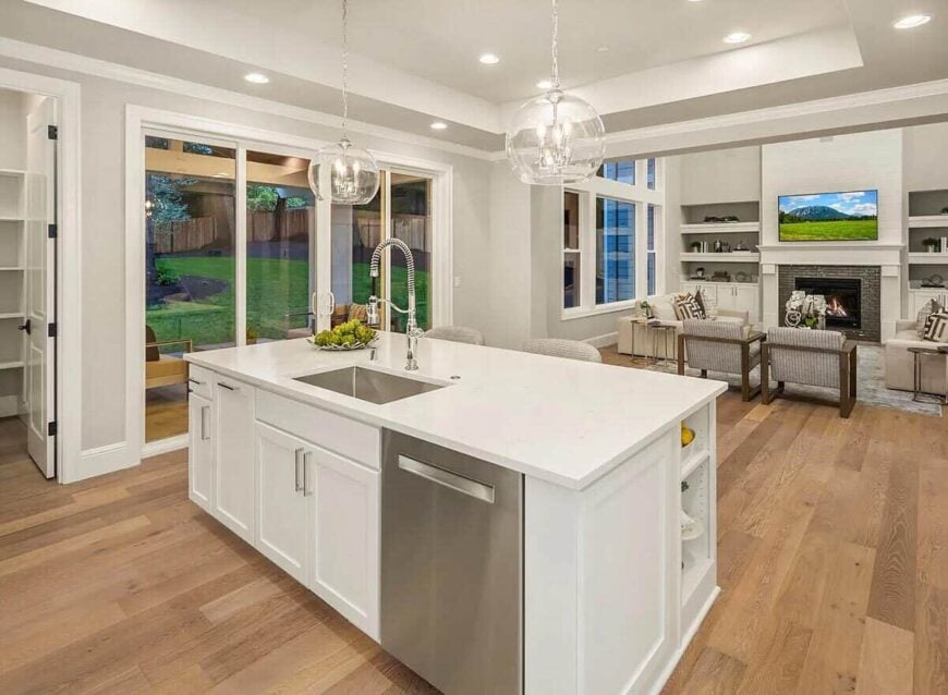 The kitchen island brightened by a couple of glass globe pendants overlooks the great room.