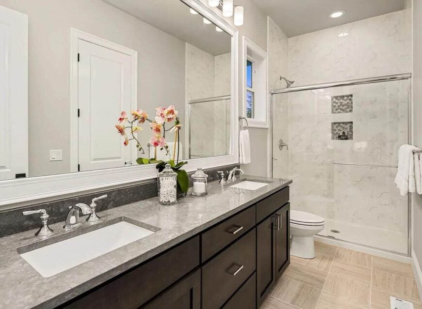The guest bathroom offers dual sink vanity, a toilet, and a walk-in shower.