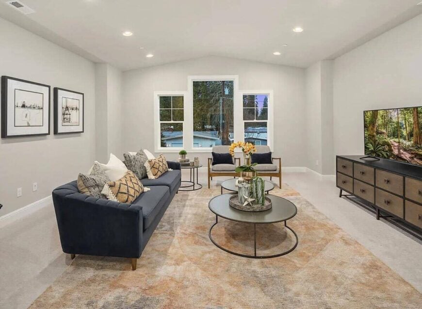 Family room with a gray sofa, cushioned armchairs, nesting coffee table, and a large TV.
