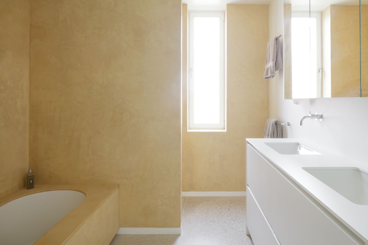 The primary bathroom painted in warm yellow with built-in bathtub.
