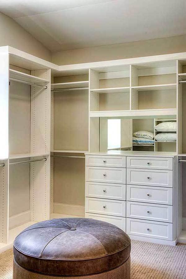 Primary walk-in closet with white built-ins and a round ottoman.
