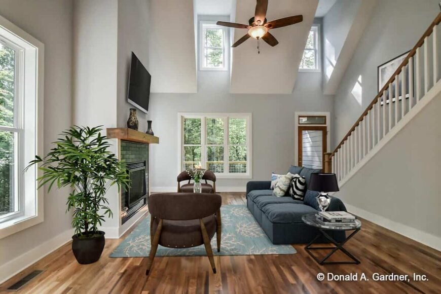Great room with a two-story ceiling, clerestory windows, and a brick fireplace topped with a wall-mounted TV.