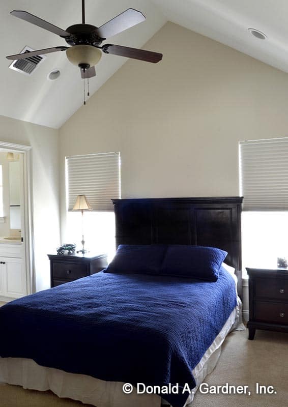 The primary bedroom has dark wood furnishings and a cathedral ceiling mounted with a fan.