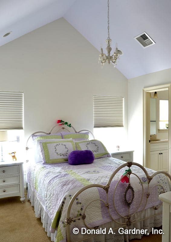 This bedroom features an ornate metal bed flanked by white nightstands and windows.