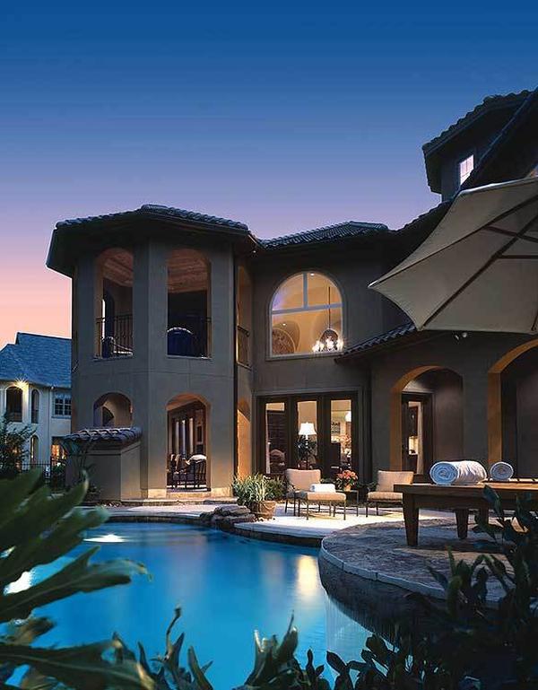 View of the house from the backyard showcasing its covered lanais and pool terrace.