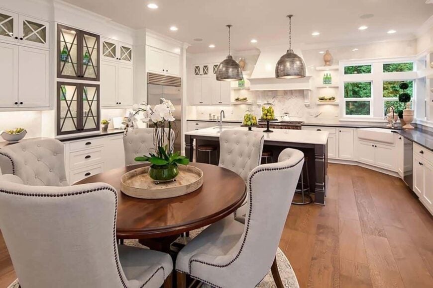 The breakfast nook offers a round dining table paired with beige tufted chairs.