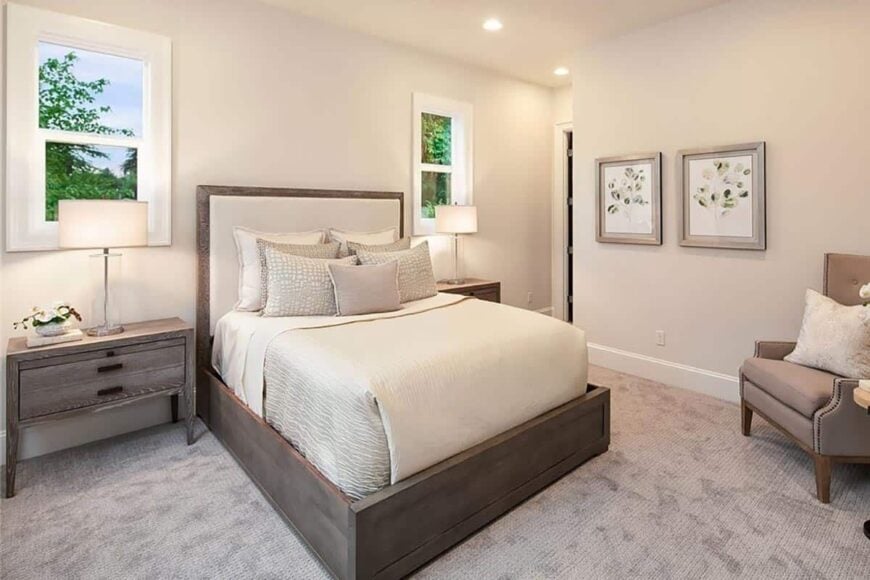 This bedroom has natural wood furnishings, a carpeted floor, and beige walls adorned with framed artworks.