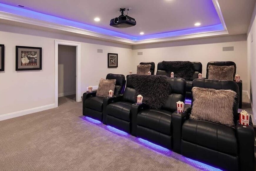 Purple led lights on the flooring and tray ceiling highlight the media room.