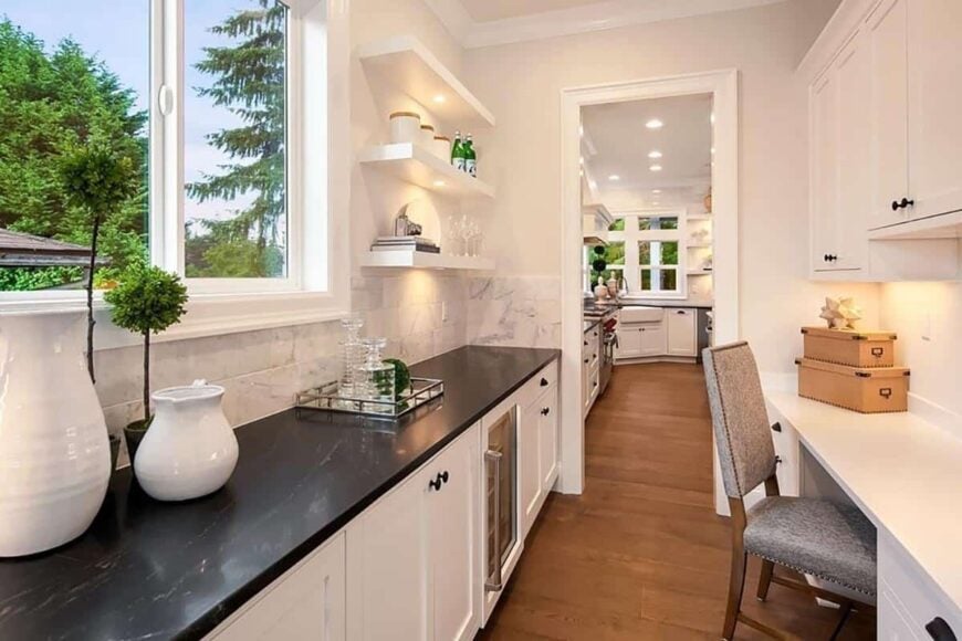 Butler's pantry with contrasting black and white counters, floating shelves, and sliding windows that invite natural light in.