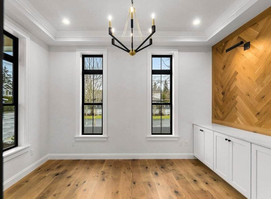 Den with a contemporary chandelier and a built-in bar graced with a herringbone wood accent wall.