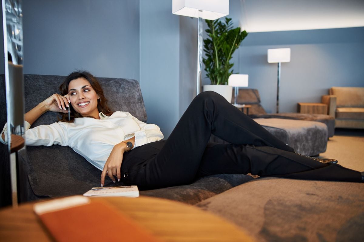 A lady lying on a sofa holding a phone.