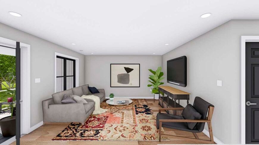 Living room with a gray sofa, a wall-mounted TV, and a vintage area rug that lays on the hardwood floor.