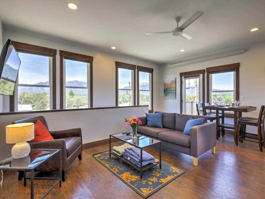 Combined living room and dining area with leather and fabric seats, glass-top tables, and surrounding windows overlooking the serene landscape.Combined living room and dining area with leather and fabric seats, glass-top tables, and surrounding windows overlooking the serene landscape.