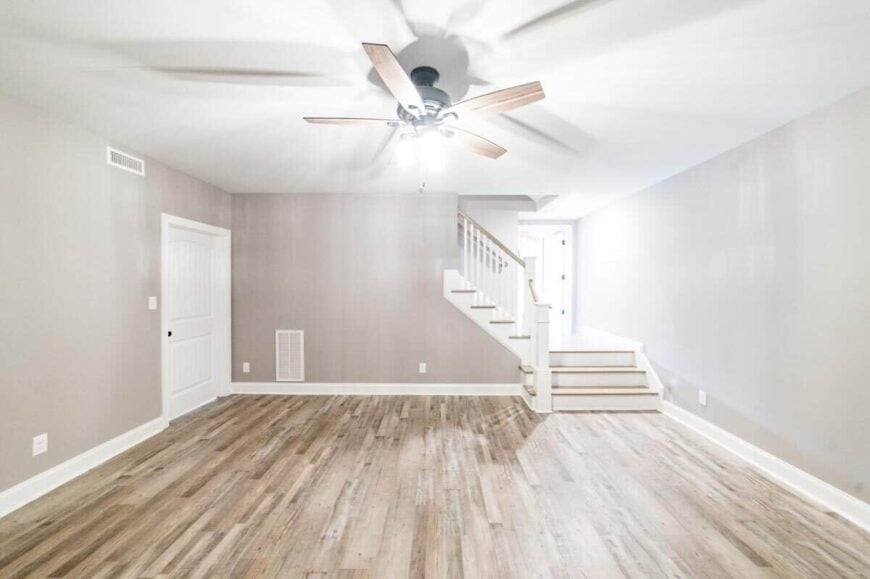 The basement has a hardwood floor, gray walls, and a staircase leading to the main living space.