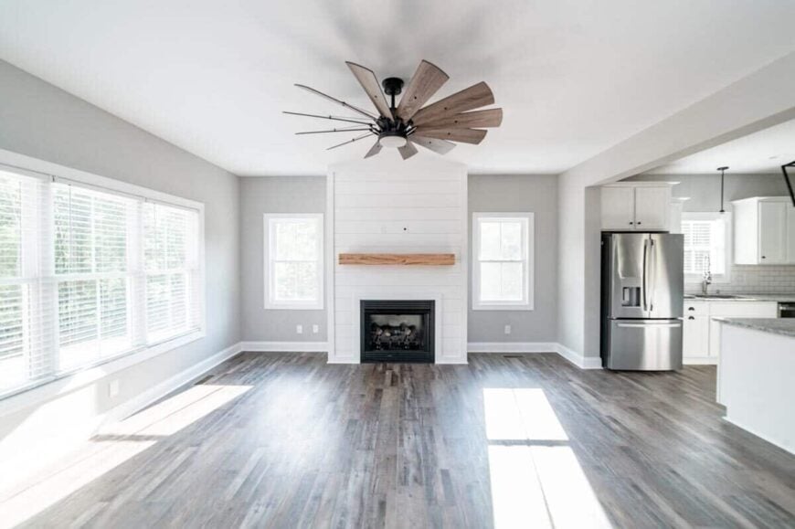 Family room with a fireplace and lots of white framed windows inviting natural light in.