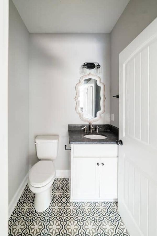 Decorative tiled flooring and an ornate mirror adorn this powder room.