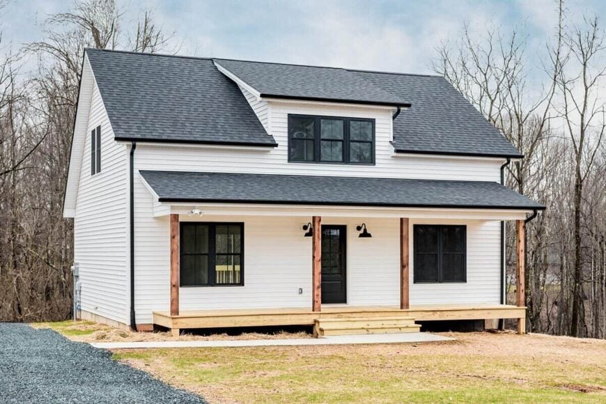 Front exterior view with horizontal lap siding, a central shed dormer, and a covered entry porch lined with rustic beams.