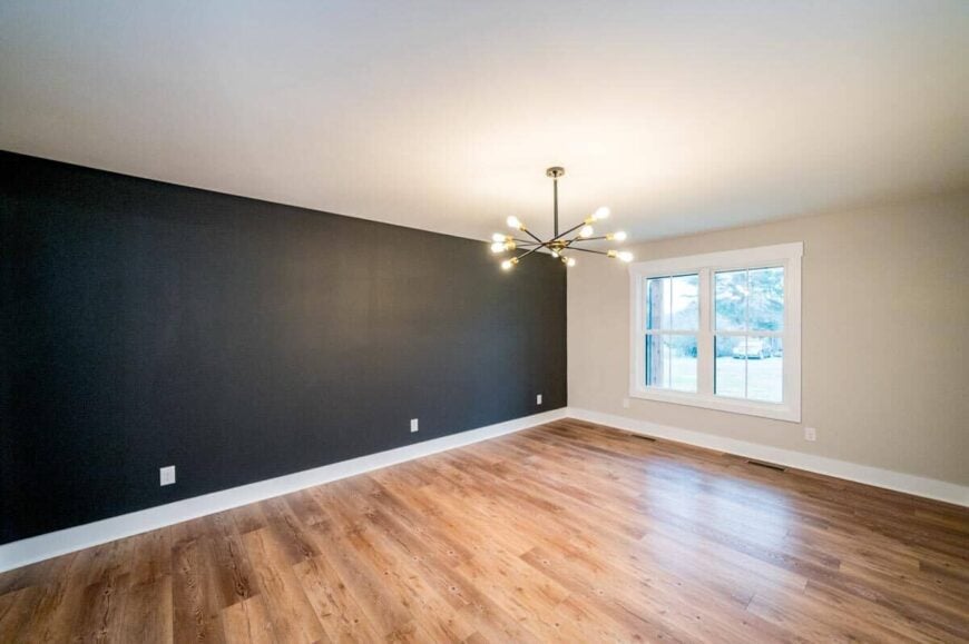 Primary bedroom with a contemporary chandelier, a hardwood floor, and a black accent wall.