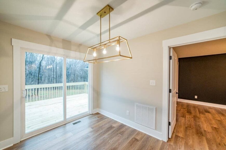 The dining space is well-lit by a gold, linear chandelier.