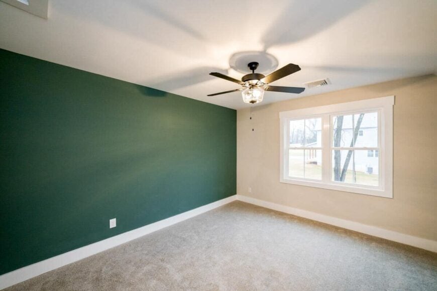 A green accent wall adds a pop of color to this beige bedroom.