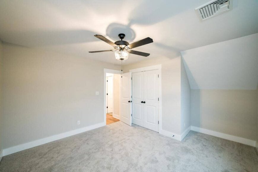 This bedroom has carpet flooring and a walk-in closet concealed behind the white double doors.