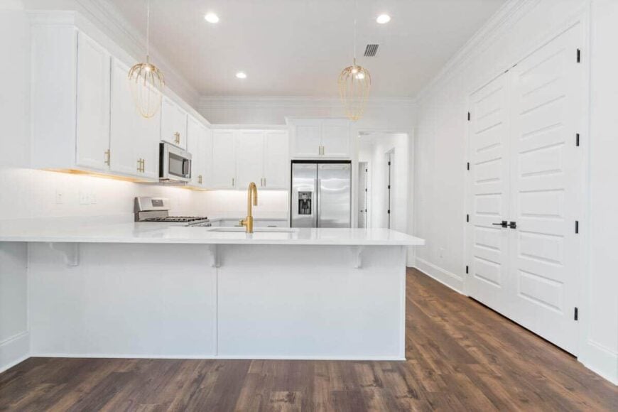 Kitchen with white cabinetry, stainless steel appliances, and a peninsula fitted with a sink.