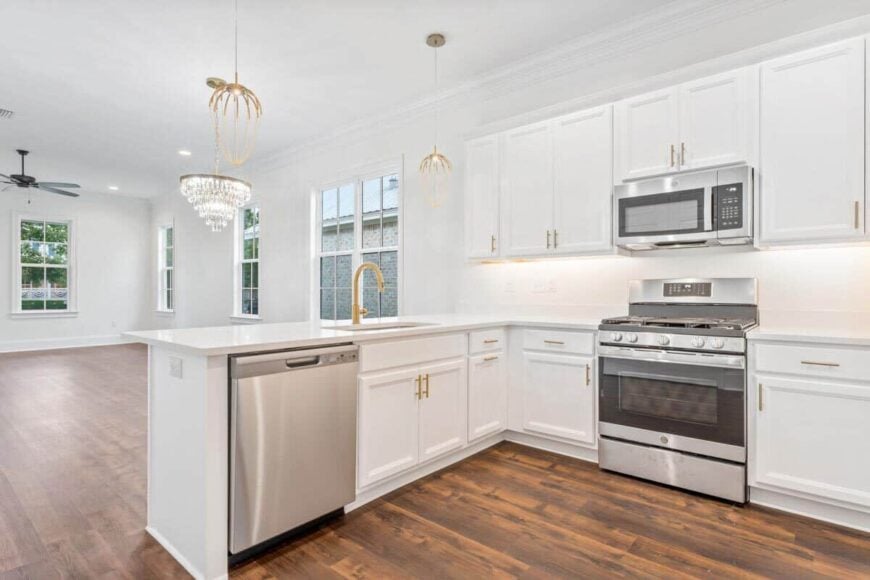 Brass hardware and fixtures accentuate the pristine white kitchen.