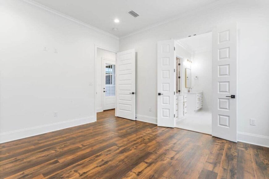 The primary bedroom includes a private bathroom enclosed in white double doors.
