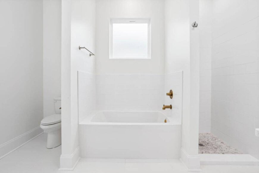 The primary bathroom includes a toilet area, a walk-in shower, and a deep soaking tub fitted with brass fixtures.