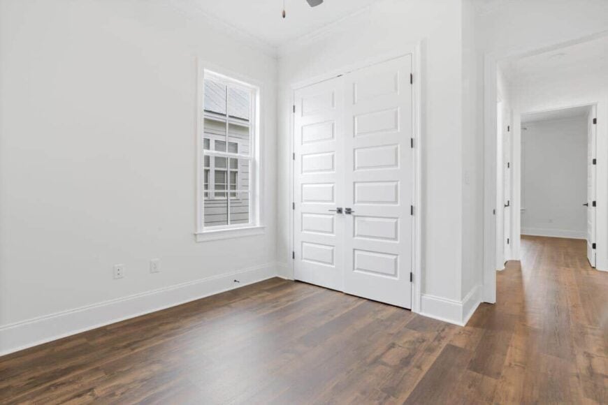 Another bedroom with a hardwood floor and a walk-in closet concealed behind the white double doors.