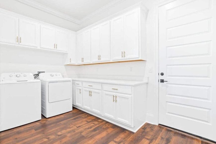 The laundry room has white appliances, a quartz countertop, and plenty of storage.