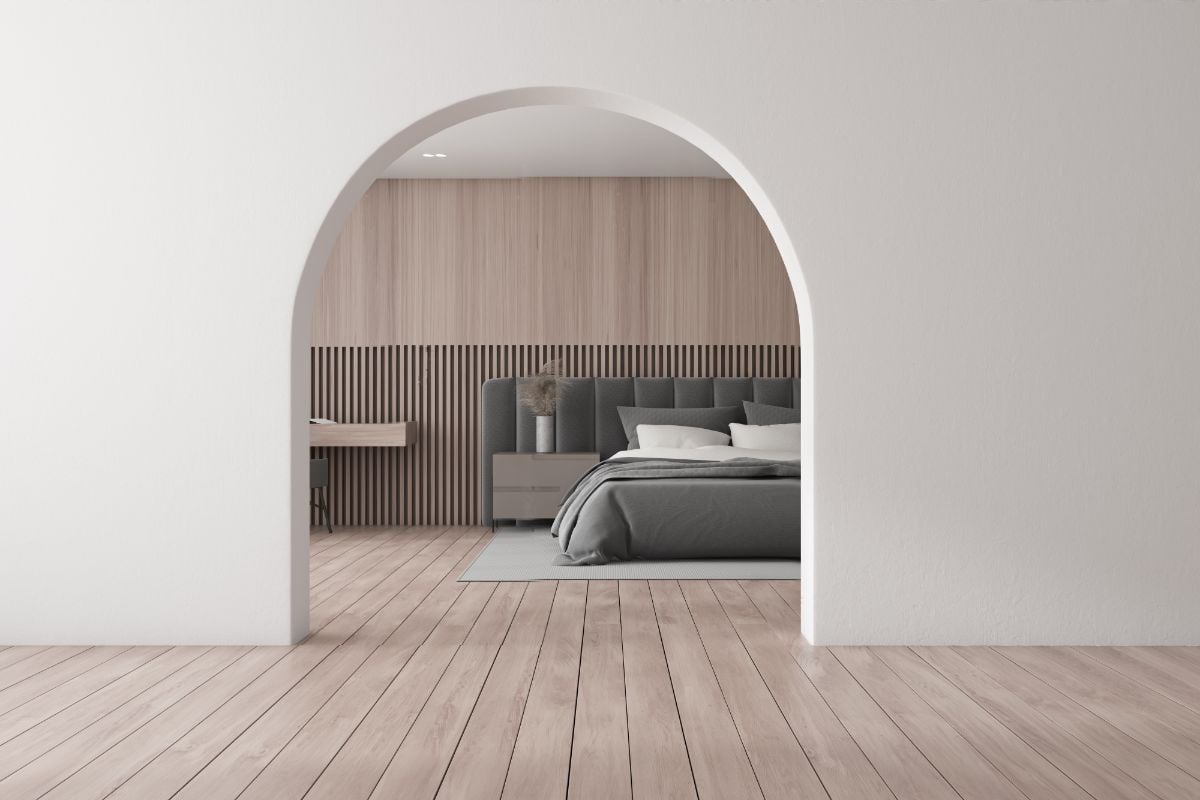 A bedroom with arched door and wooden floor.