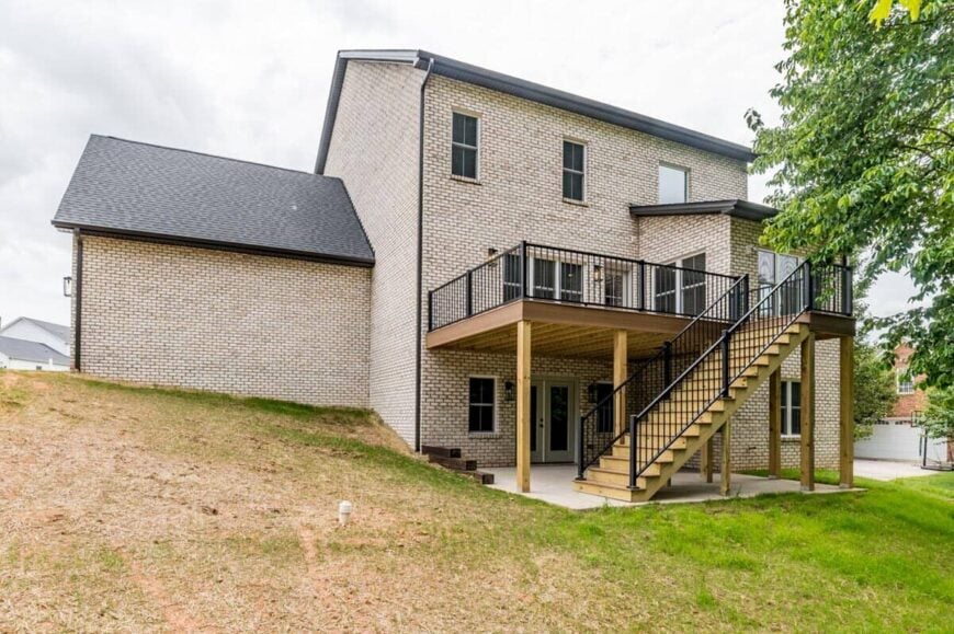 Rear exterior view with a covered patio and a staircase leading to the sun deck.