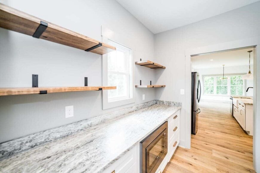 The butler's pantry is equipped with an oven, a granite countertop, and lengthy shelves.