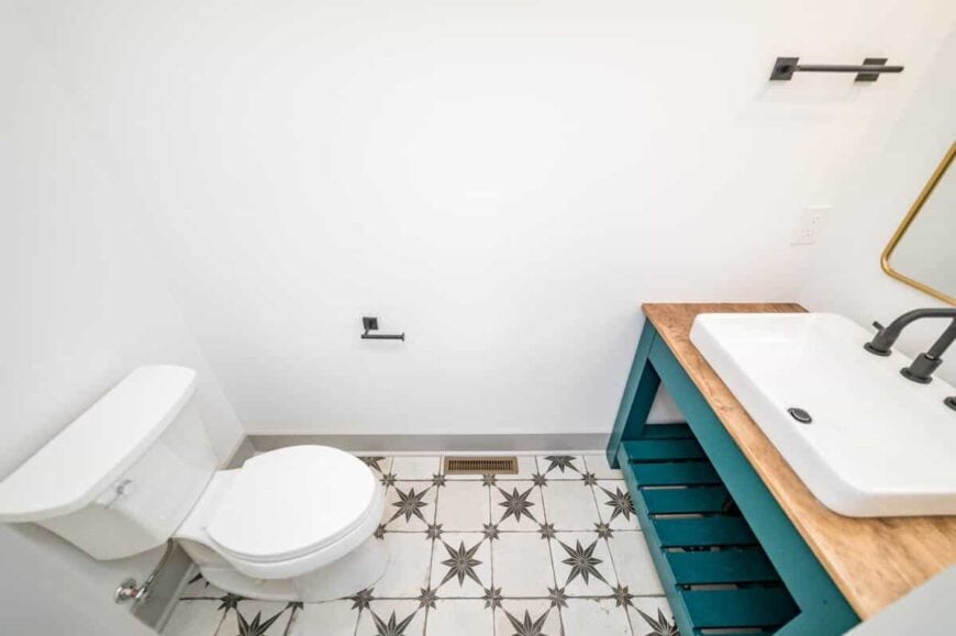 Decorative tile flooring and a washstand with a green base bring character to the powder room.