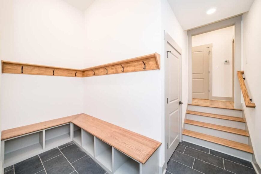 The mudroom has an L-shaped bench integrated with storage shelves underneath.