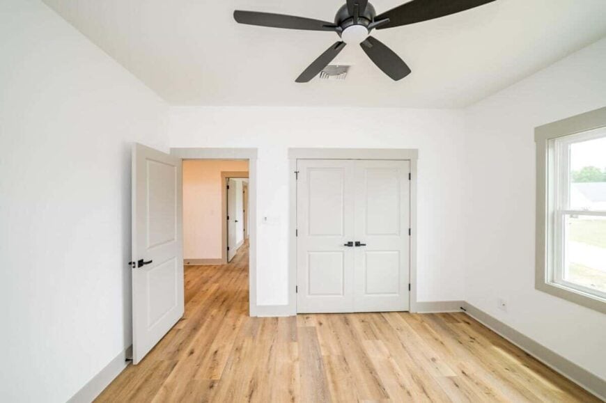 Bedroom with a wrought iron ceiling fan and a walk-in closet concealed behind the double doors.
