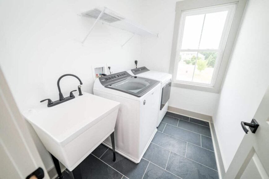 The laundry room is equipped with a washer and dryer, a white metal shelf, and a utility sink.