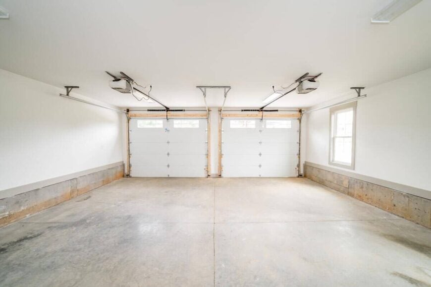 The double garage has a concrete tiled floor, small windows, and automatic doors.