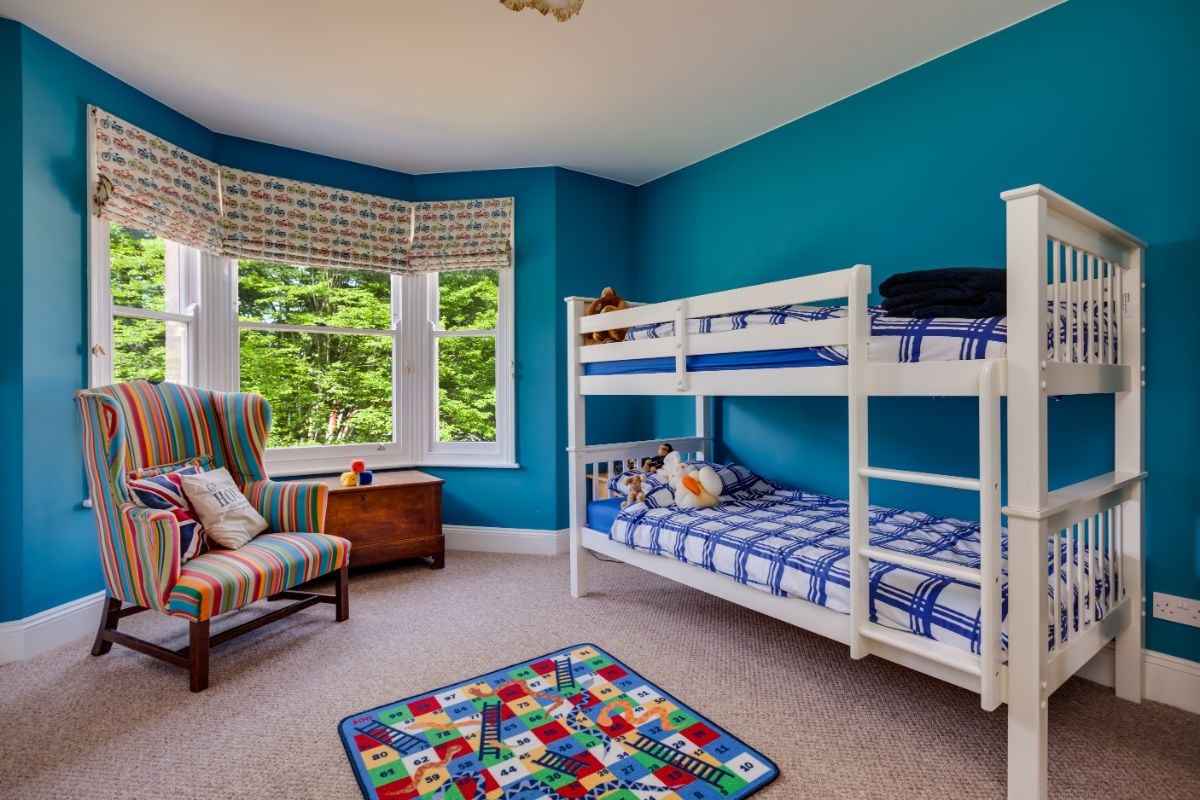 A room with bunked beds and bow window.